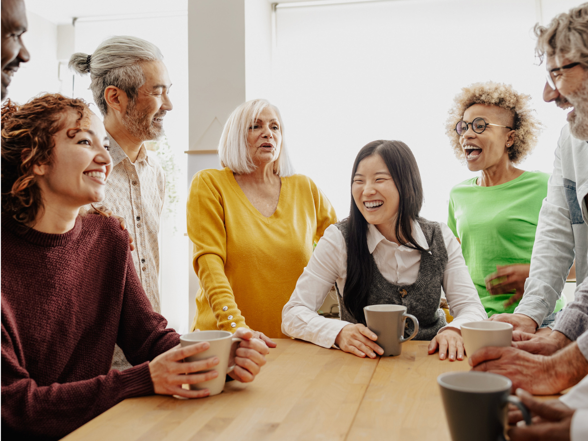 A group of people sit around a table smiling and chatting