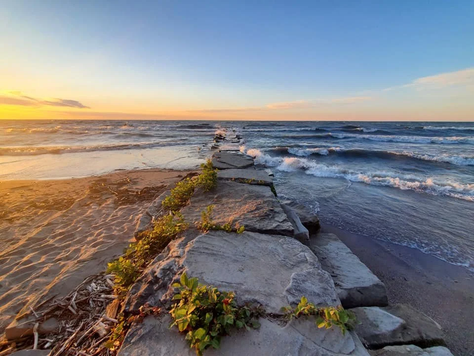 Jetty extends from the beach into Lake Erie at sunset.