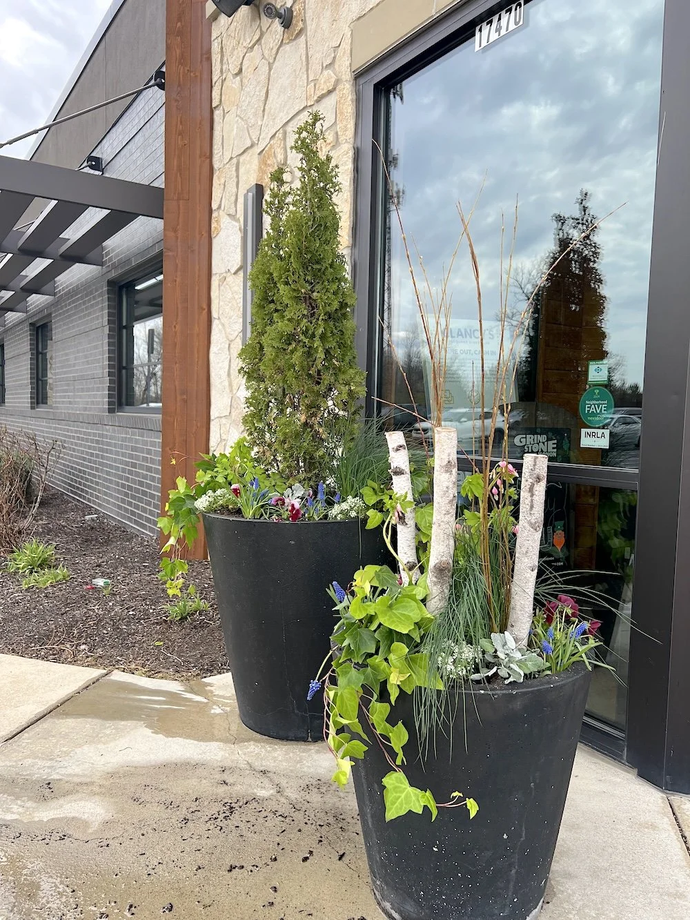 Fresh, vibrant spring planters overflowing with seasonal blooms and lush greenery at Grindstone on the Monon in Westfield, Indiana. These professionally designed outdoor planters feature a mix of colorful flowers, textured foliage, and natural elemen