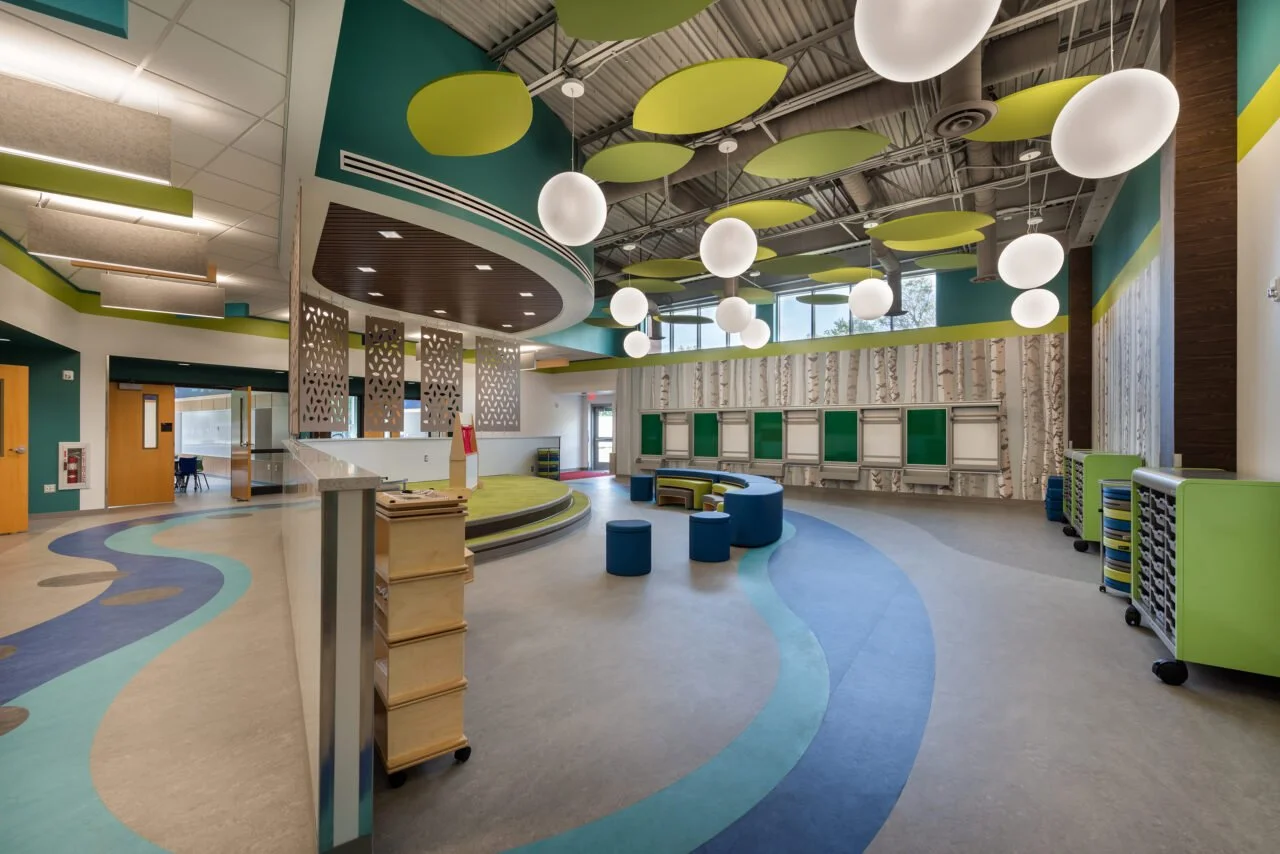 Colorful and spacious indoor room, possibly a classroom or play area, with patterned floors, modern lighting fixtures, and decorative partitions.