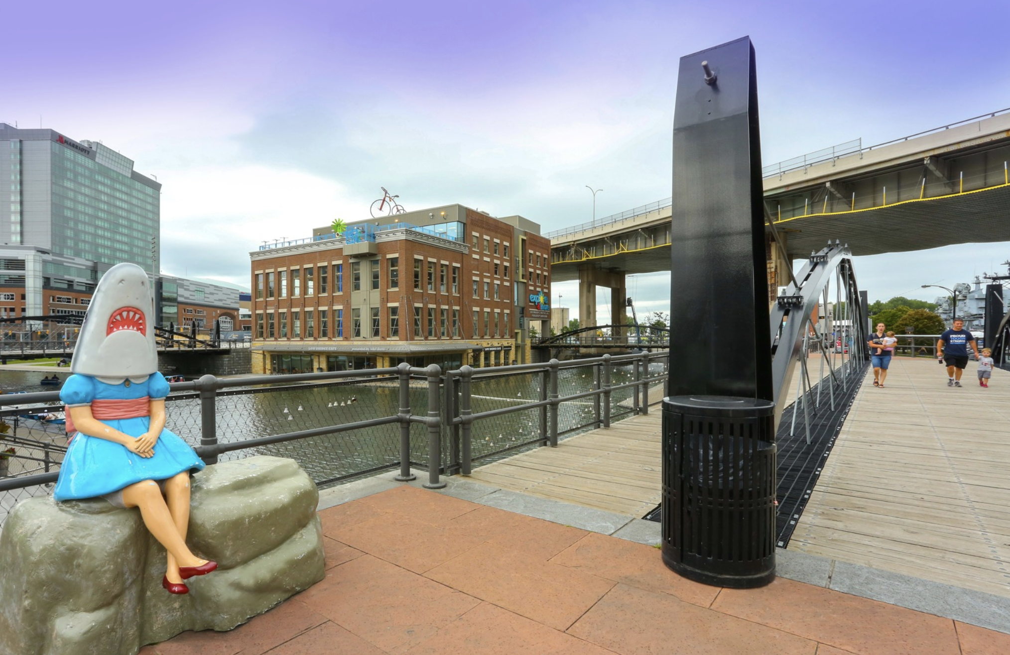 Buffalo's Shark Girl sculpture sits at Canalside with Explore & More museum in the background.