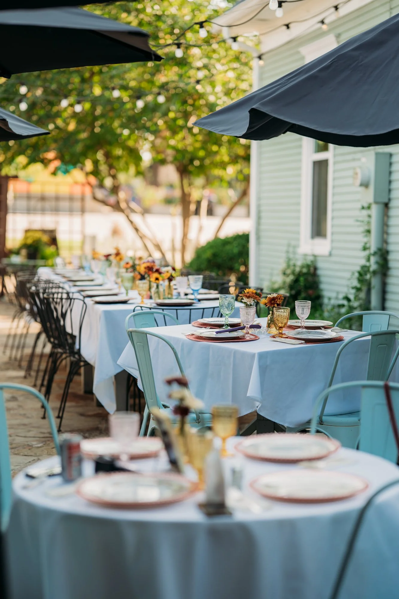 Backyard reception tables under blue umbrellas at The Vintage House in Overland Park.
