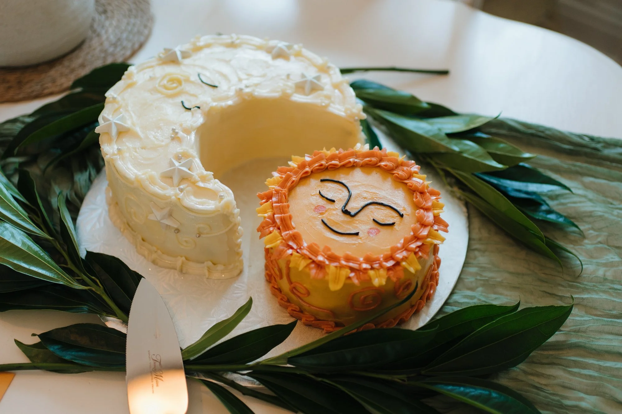 Sun and moon wedding cakes by Cakes by Cookie on green leaves.