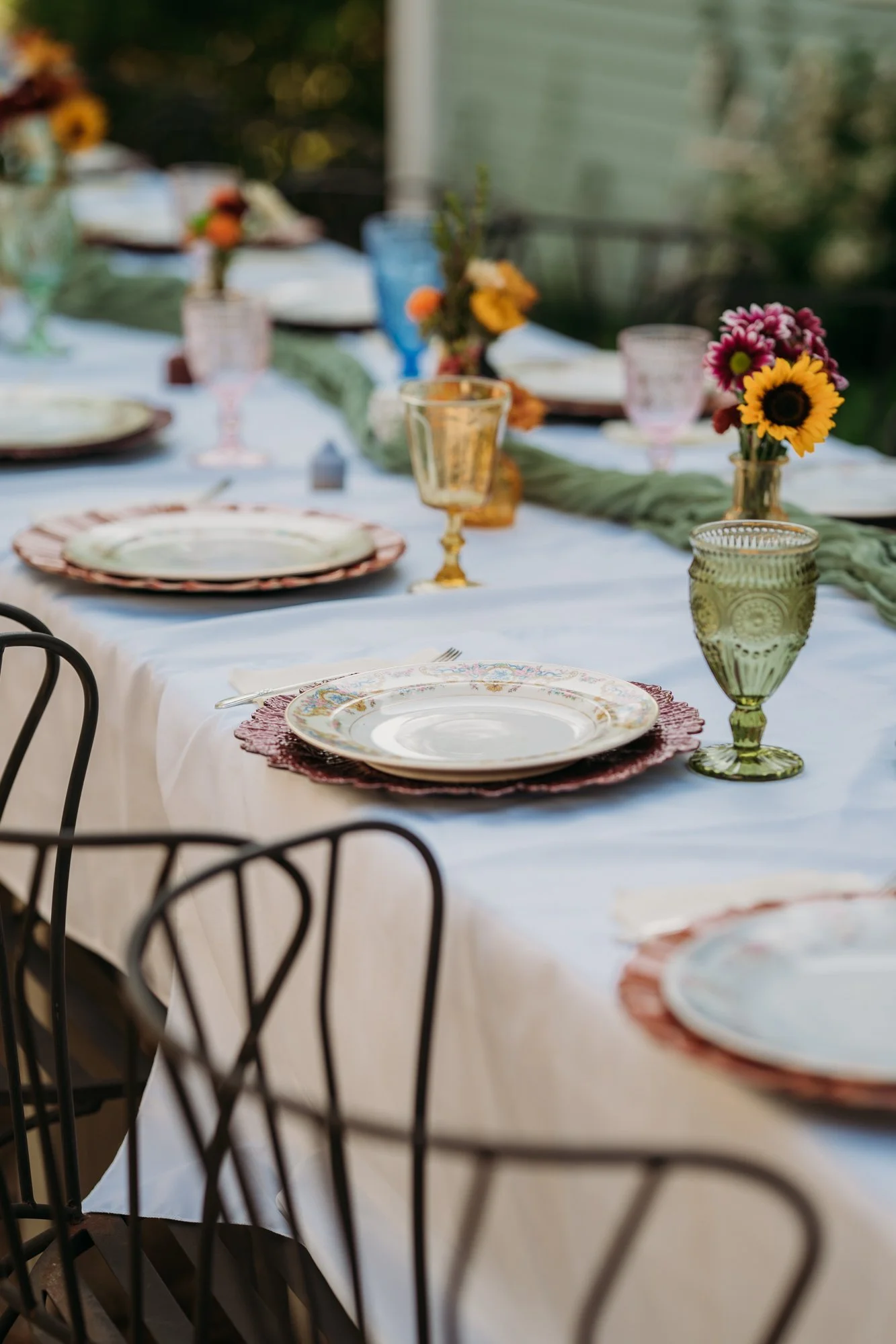 Reception table with vintage plates, gold glasses, and sunflowers at The Vintage House in Overland Park.