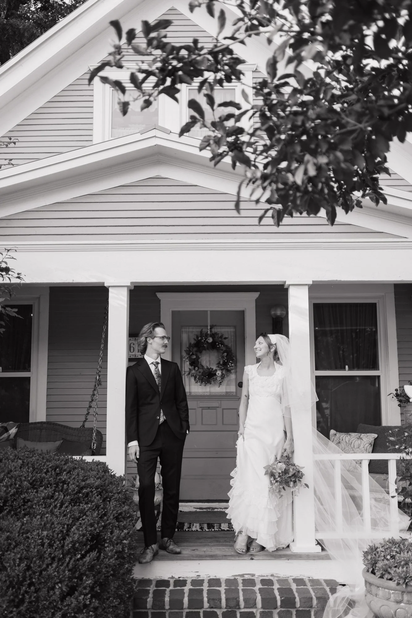 Black and white photo of Zoe and Hunter on the front porch of The Vintage House.