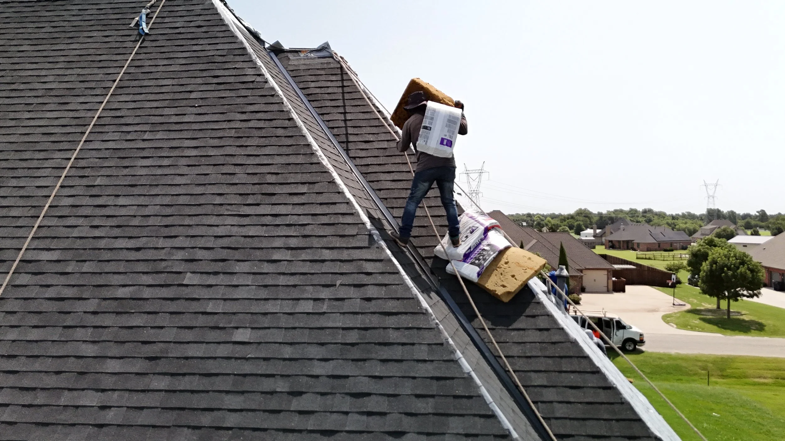 Person working on a sloped residential roof, carrying insulation materials.