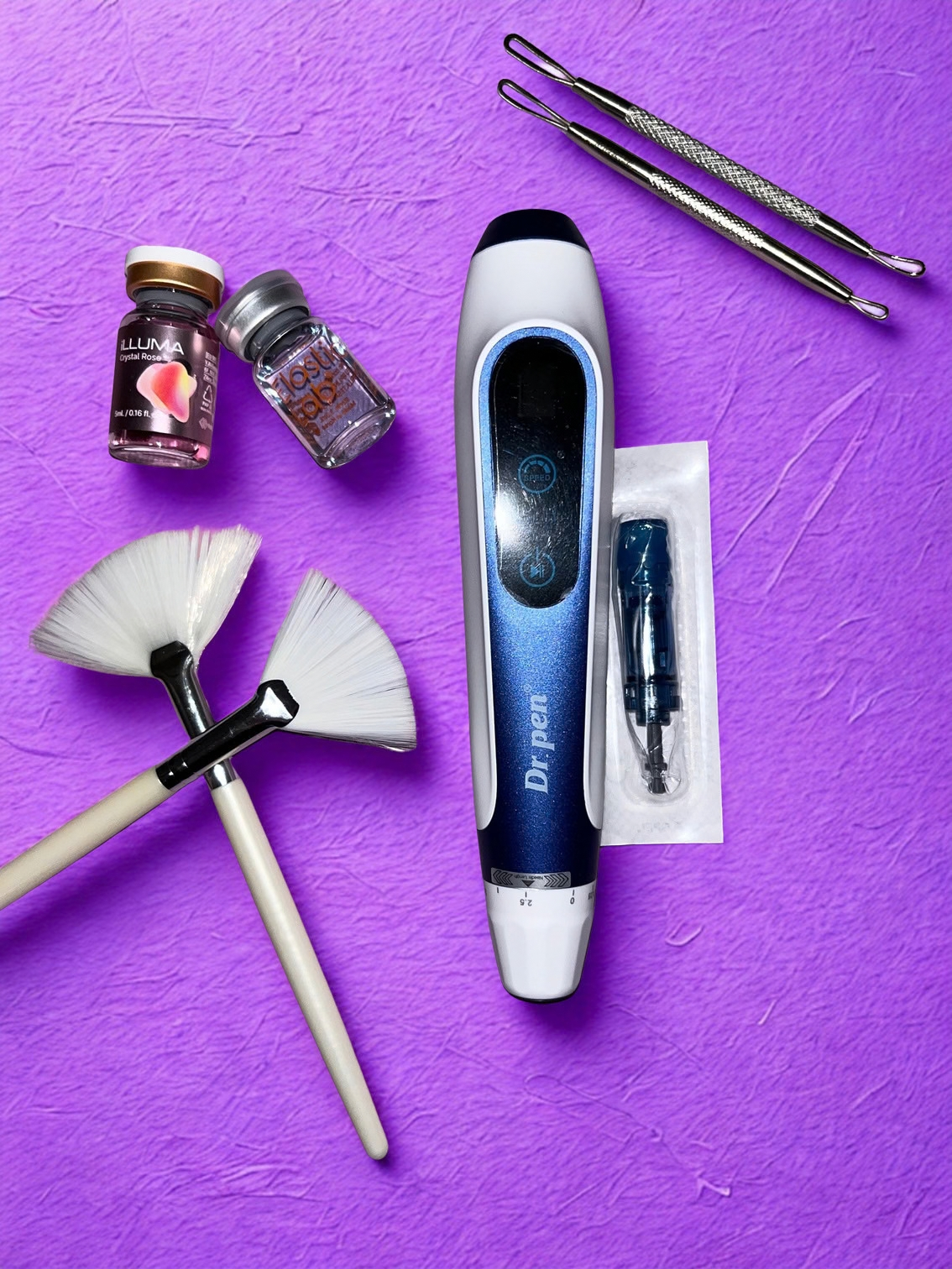 At-home dermaplaning tool kit including Dermaplane device, two dermaplaning blades, two fan brushes, micro-needling pen, and two bottles of pink and silver nail powders on a purple textured background.