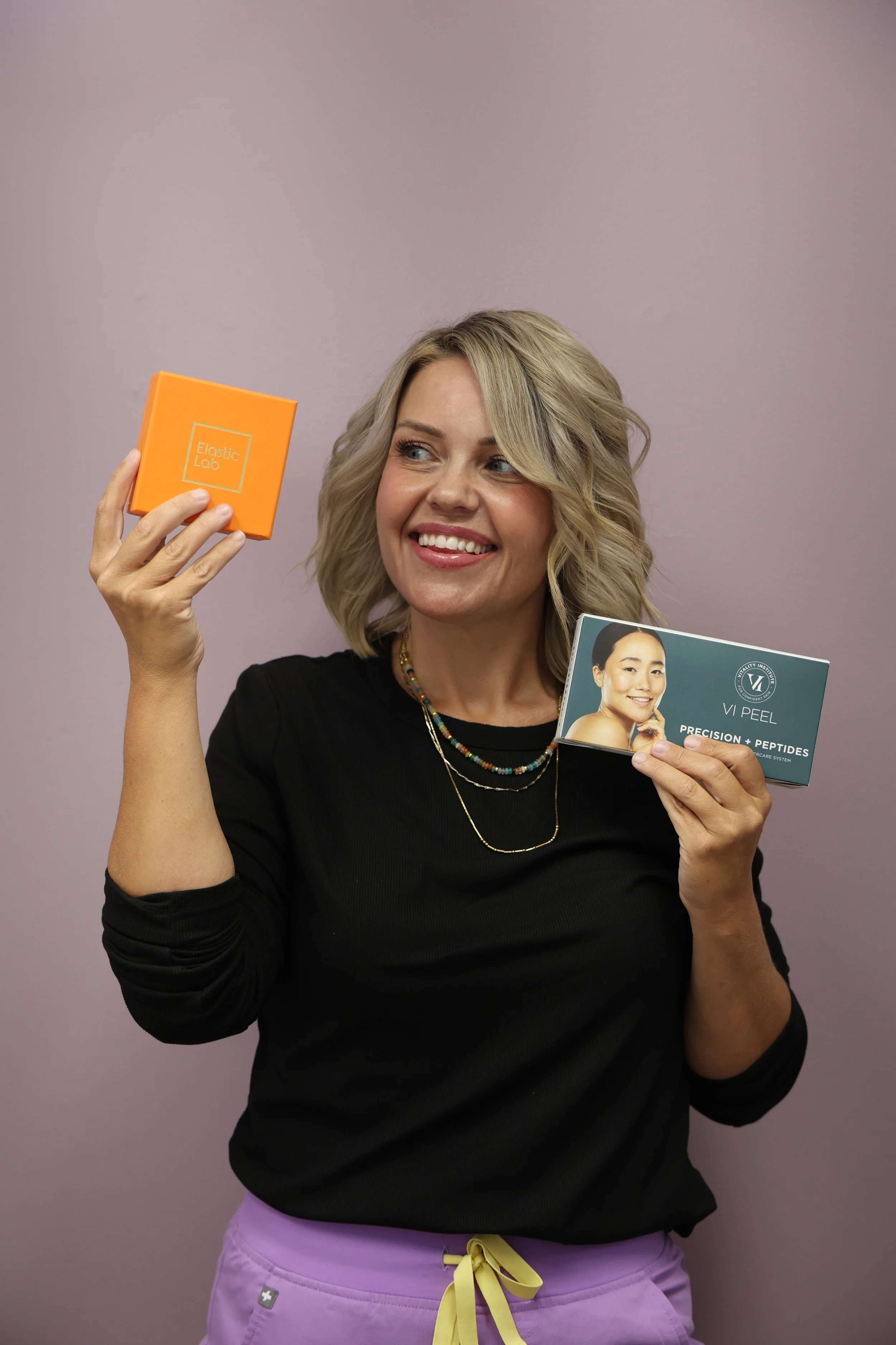 Alicia Moore an Advanced Esthetician holding Elastic Labs and VI Peel for your next facial appointment.