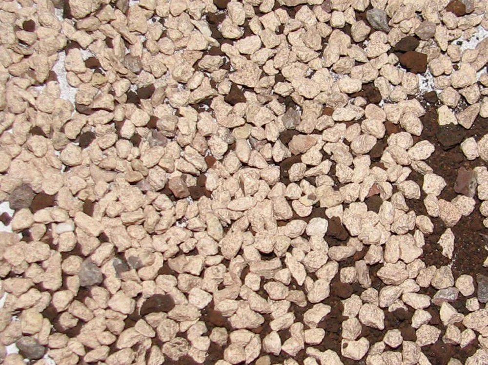 Close-up view of light brown gravel-like media for removing heavy metals from water.