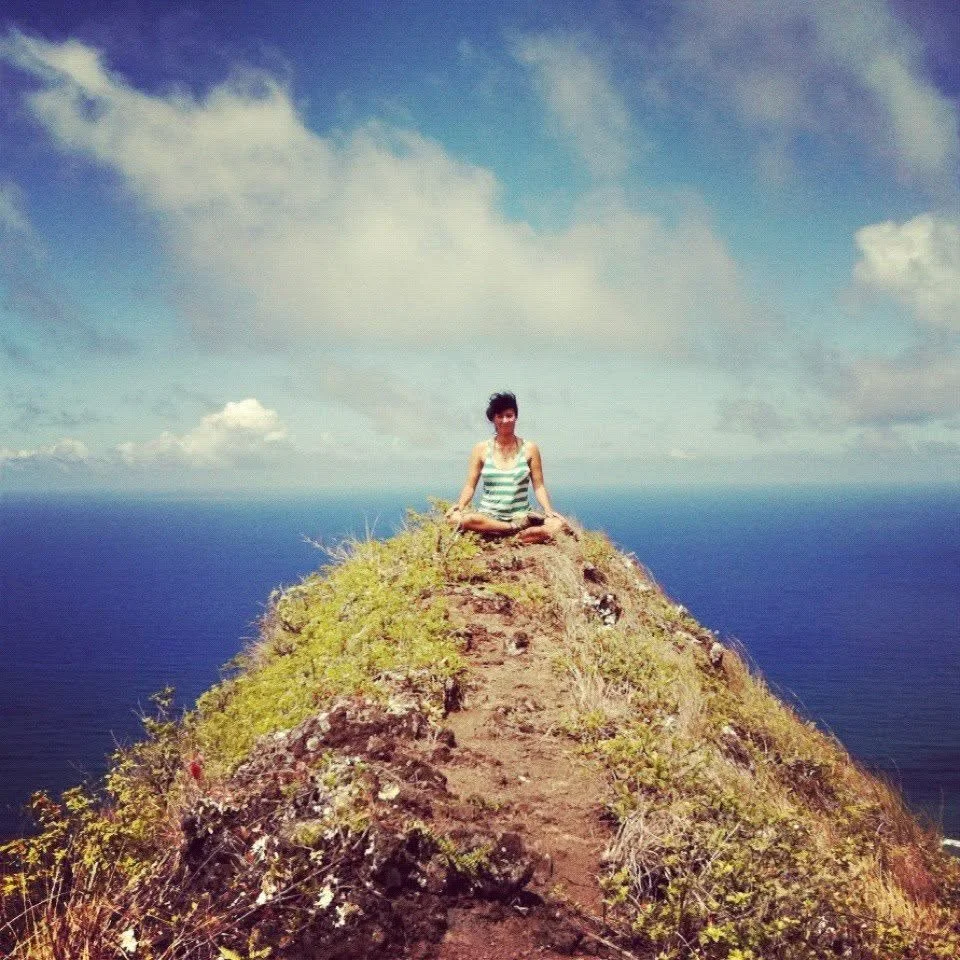 woman sitting on top of mountain above ocean