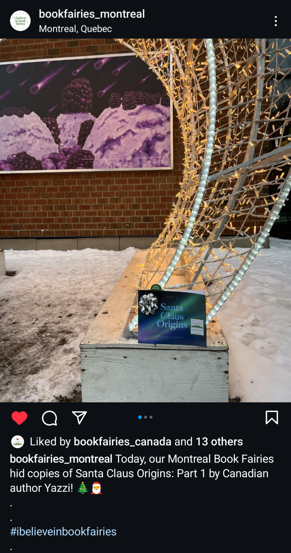 Outdoor display at the Montreal Book Fair featuring a decorated Christmas light installation and a sign for the book "Santa Claus Origins" by Yazzi, with a large illustration of blackberries and ice cream in the background.