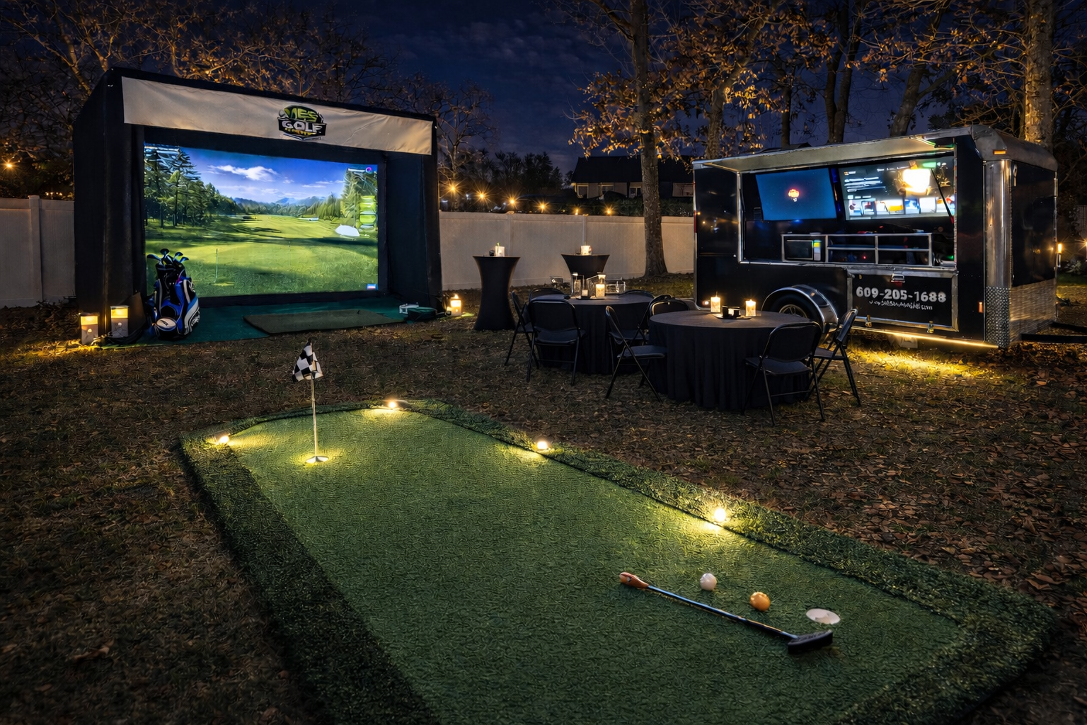 Outdoor golf simulation and mini-golf setup at night with a large screen, golf clubs, tables with candles, and a mobile game trailer.