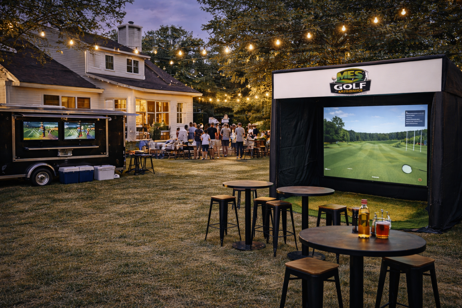 Outdoor gathering with a large group of people near a house at dusk, featuring a portable golf simulator, tables with drinks, and string lights overhead.