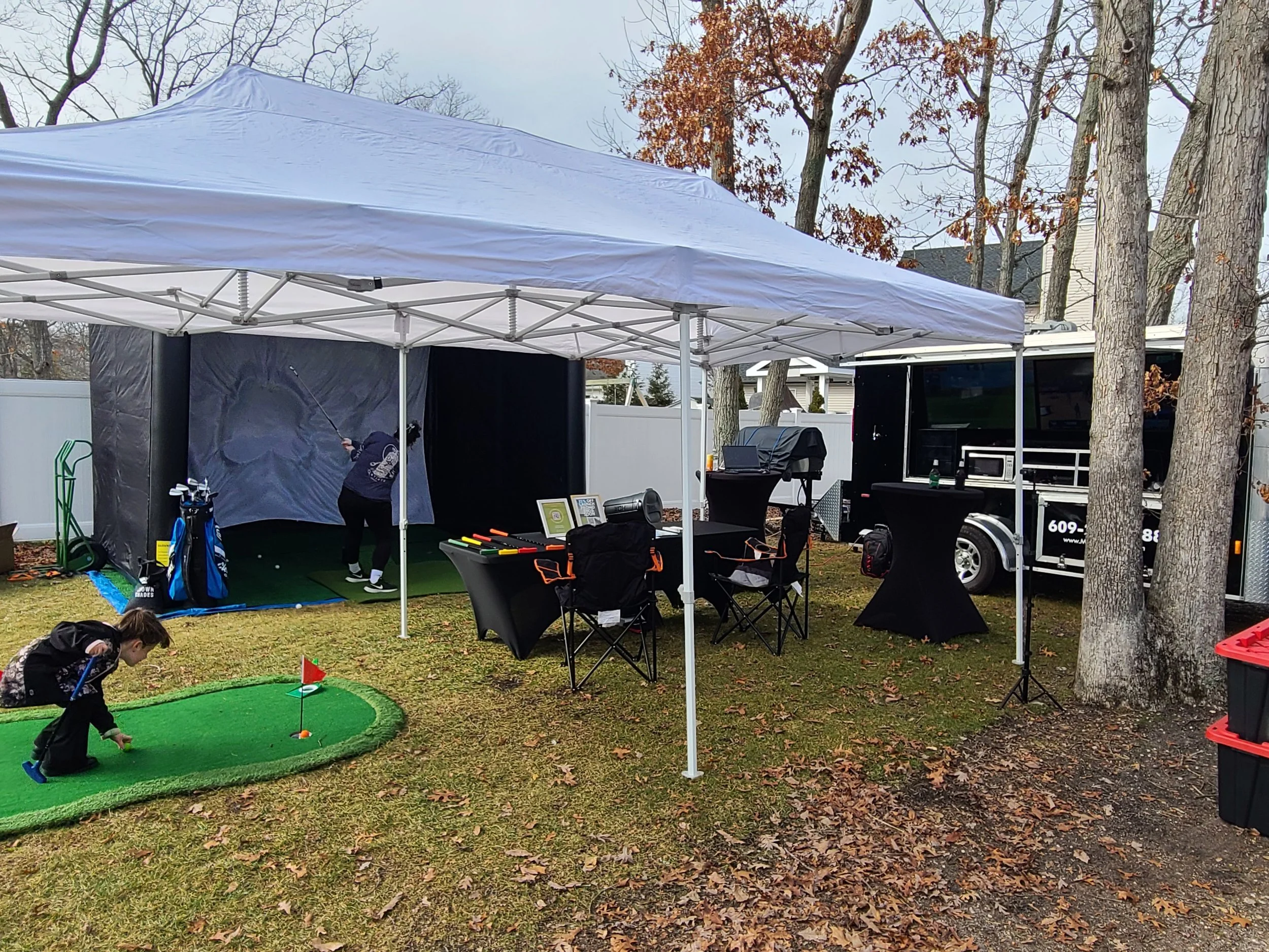Our mobile golf simulator with our tailgating/event/party trailer and putting green for the kids with tents, tables, and chairs.