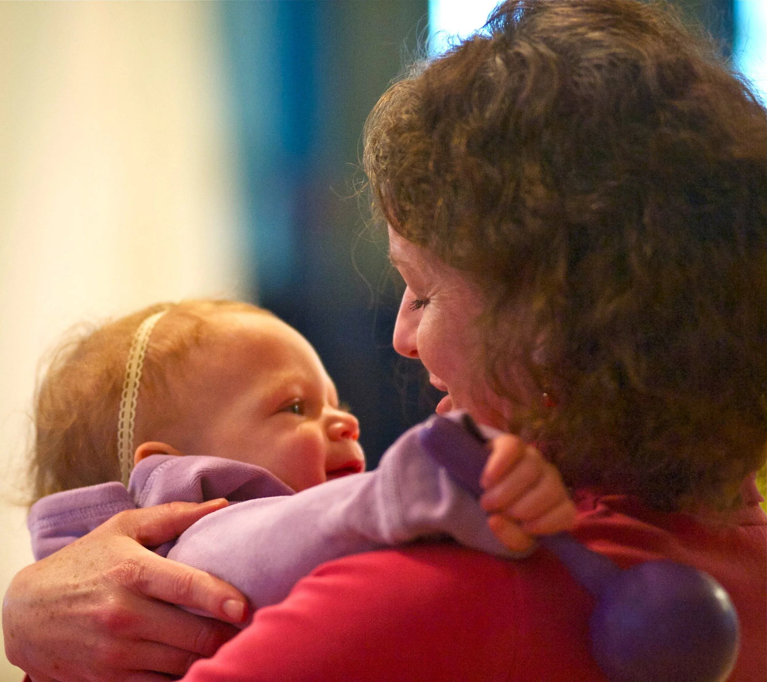 A man and a young girl share a close moment, with the man gently holding the girl, both appearing joyful and engaged.