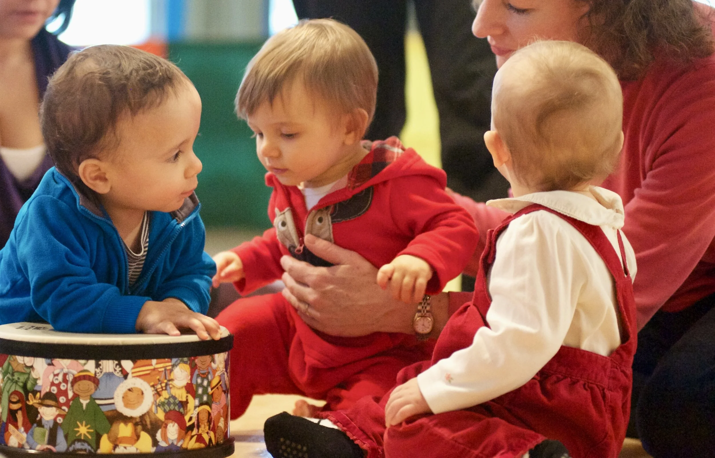 Children sitting around a table, engaging with a festive character-themed gift box during a celebration.