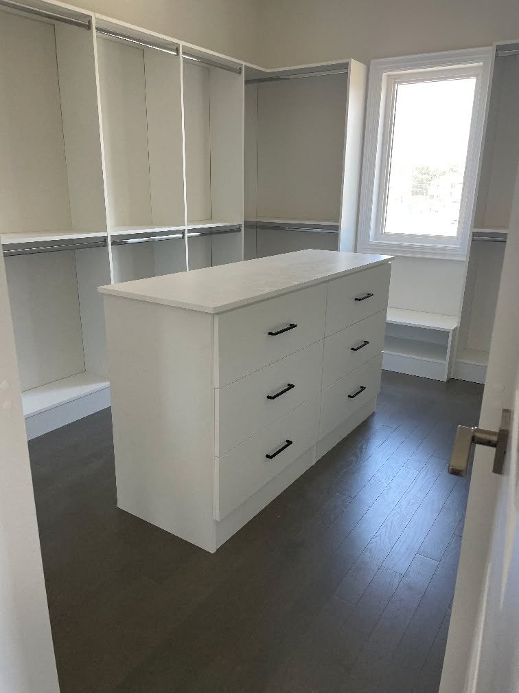 Modern walk-in closet with white shelving and drawers