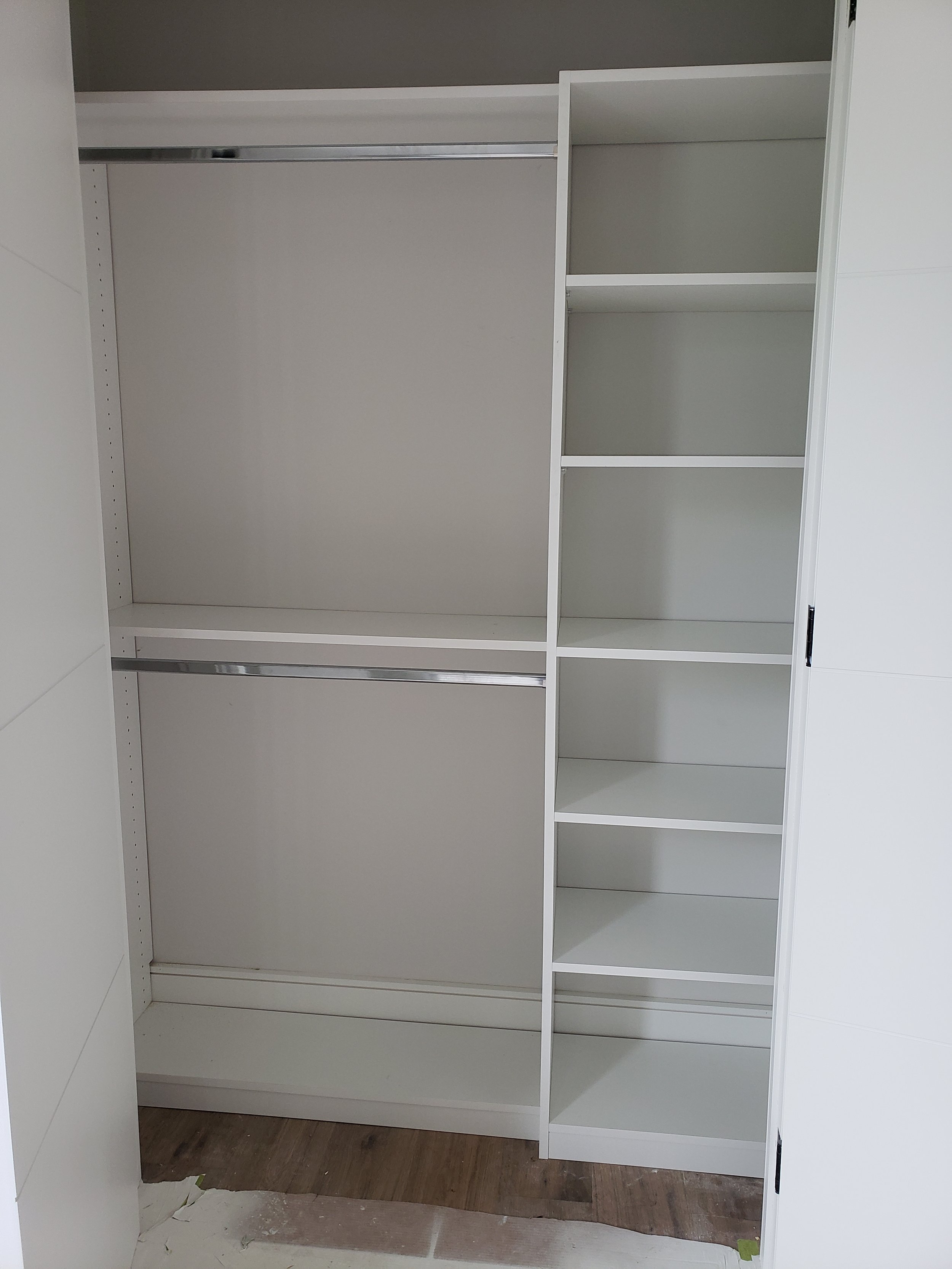 Empty white walk-in closet with hanging rods and shelves