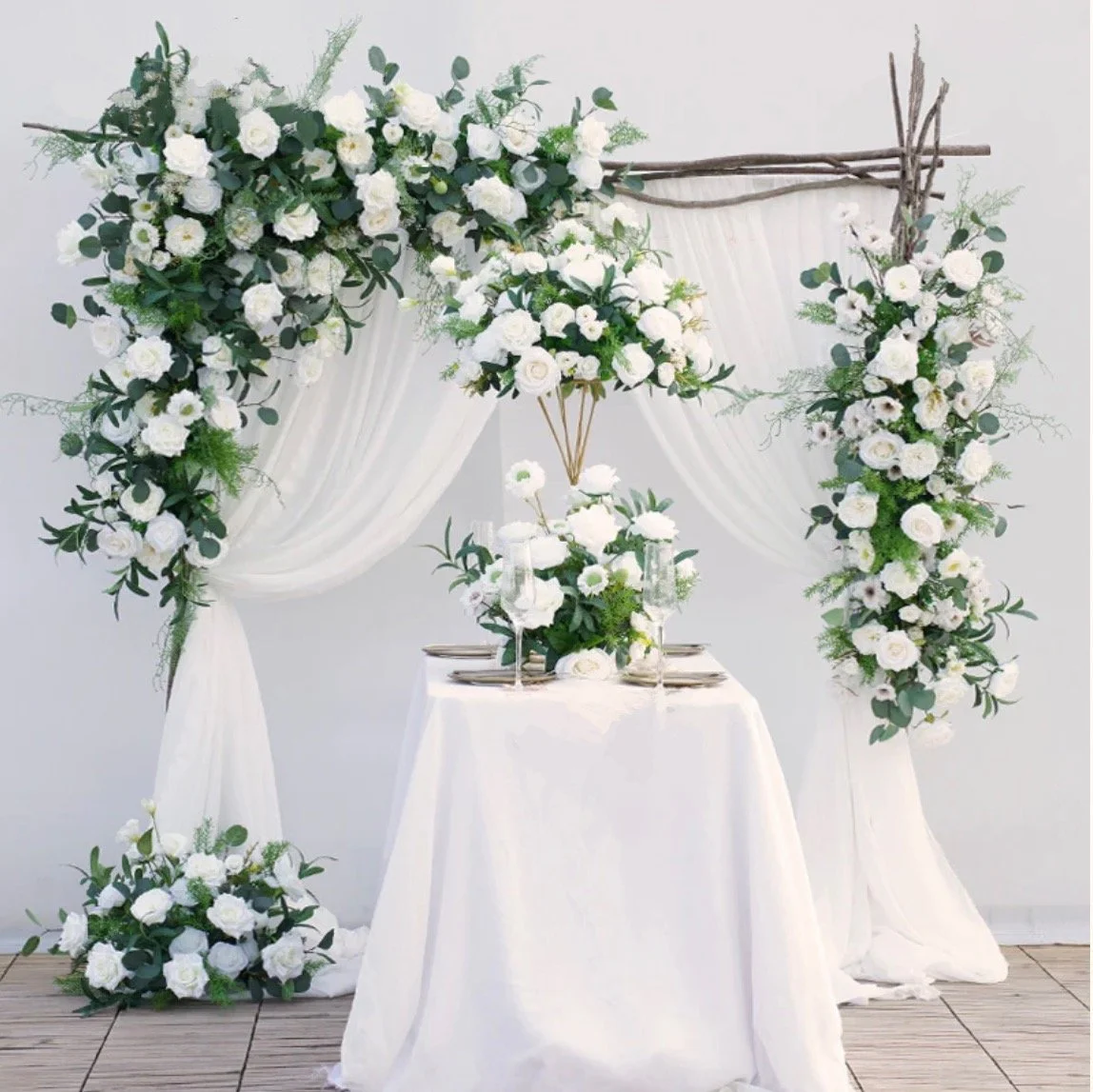 Elegant wedding ceremony arbor with lush white silk florals, greenery, and soft draping styled for a timeless vow backdrop