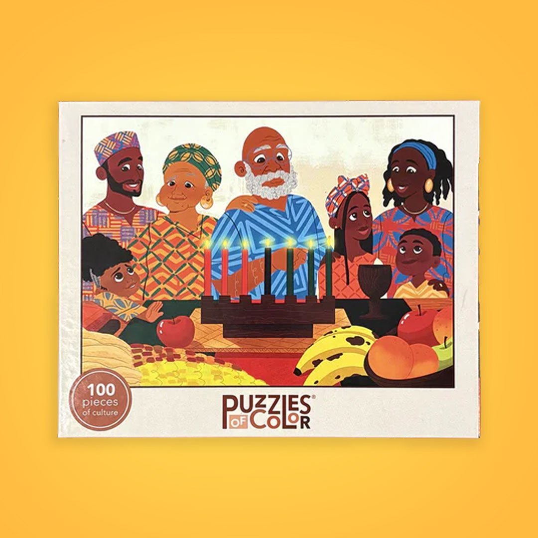 Illustrated family in colorful attire celebrating Kwanzaa, with a kinara and fruits, on a 'Puzzles of Color' box.