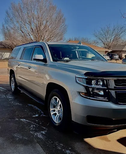 Silver SUV parked outdoors on a sunny day with leafless trees in the background.
