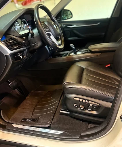 Interior of a car showing the driver's seat, steering wheel, and dashboard with controls and display.