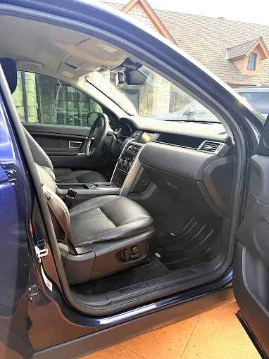 Inside view of a vehicle's front interior, showing the driver's seat, steering wheel, dashboard, and front passenger seat.