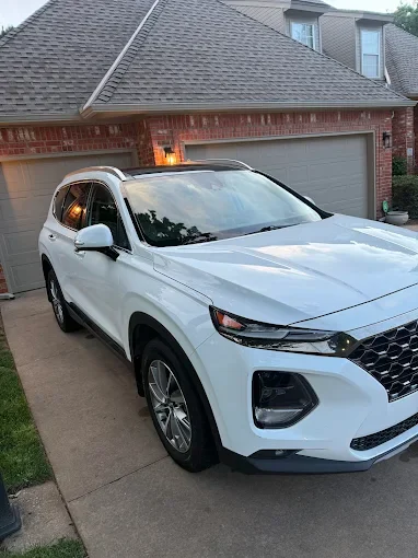 White SUV parked in driveway in front of a brick house with a two-car garage
