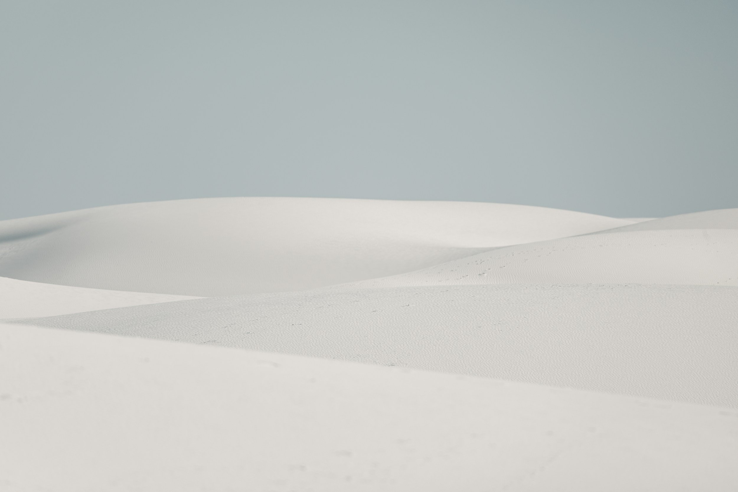 White sandy beach with gentle dunes under a clear blue sky.