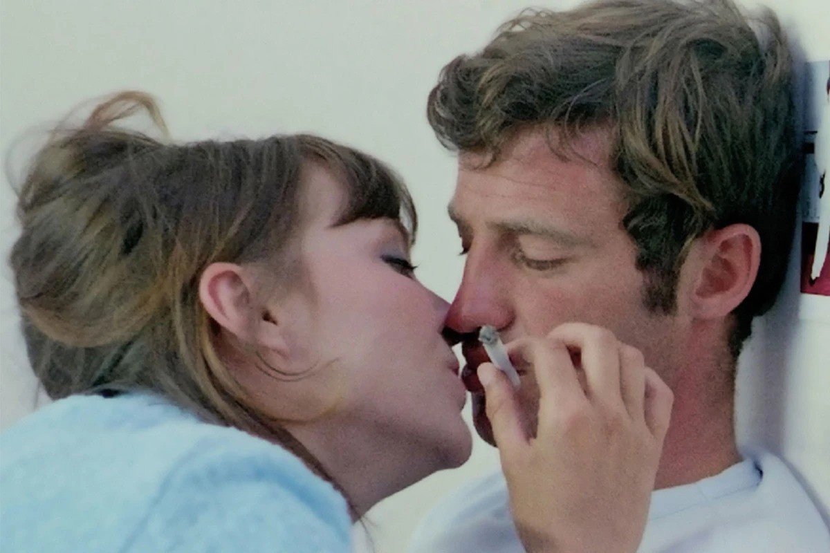 A black and white photo of two hands clasped together, positioned in front of three red heart shapes on a textured beige background.