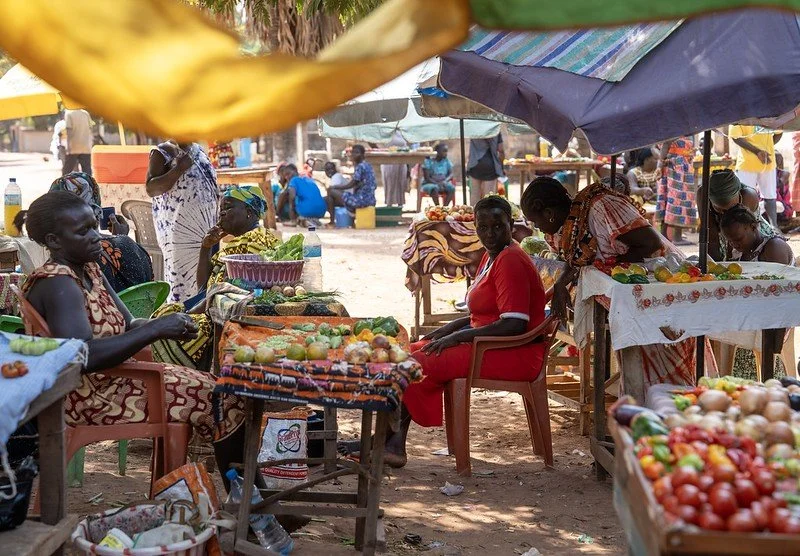 A person signing a document with two gold wedding rings resting on top of the paper.