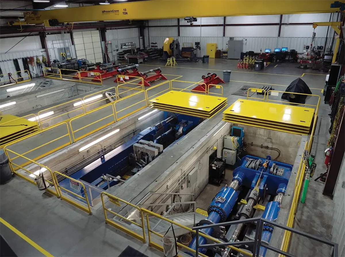 An industrial facility with large machinery, pipes, and equipment, possibly a water or utility management plant, with yellow safety railing and control areas.