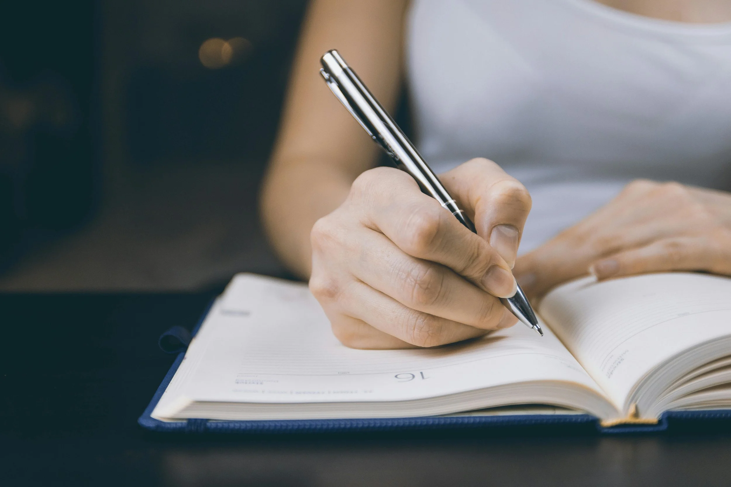 Professional woman writing in a journal to explore self-worth and people-pleasing in Orange County