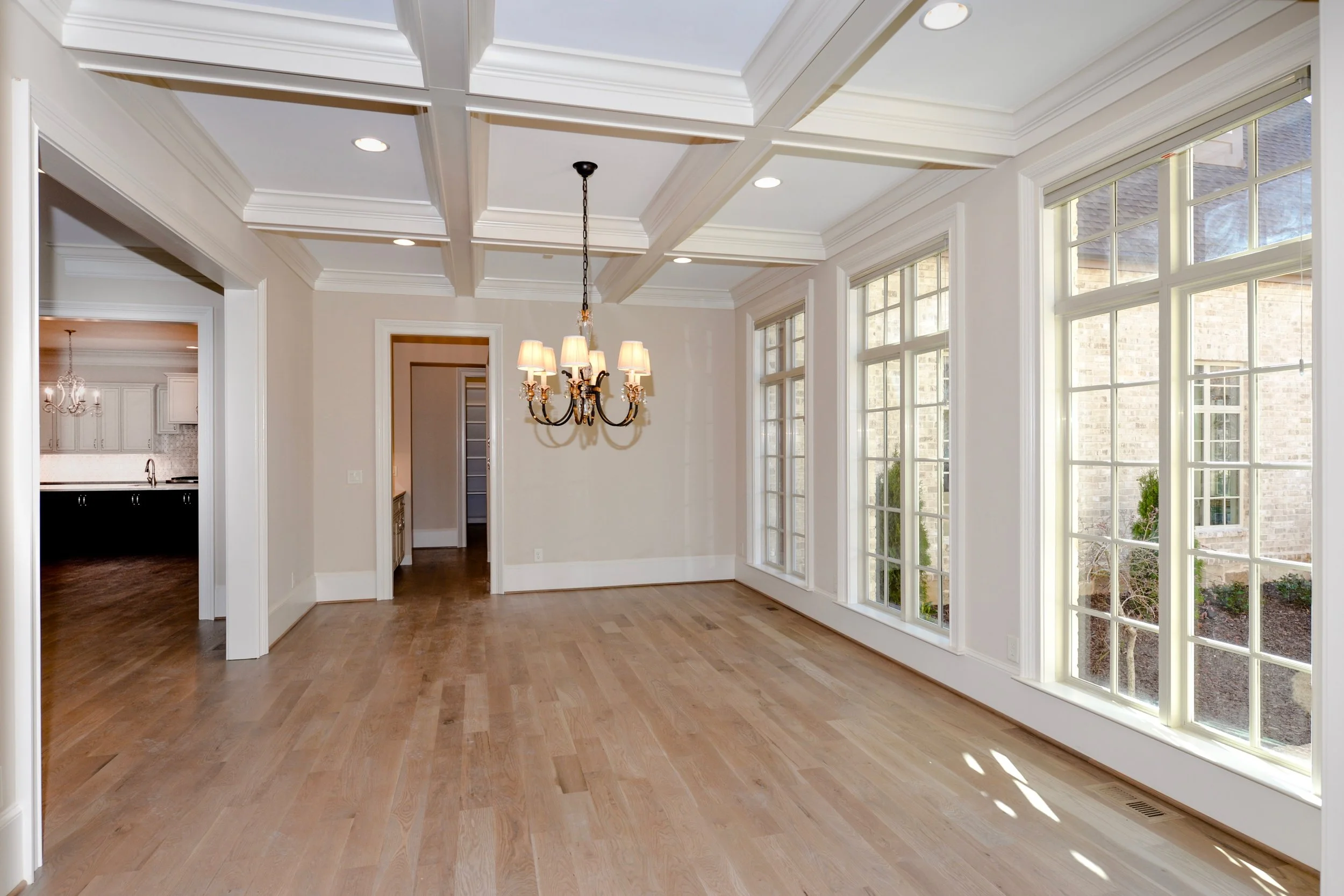 Empty dining room with large windows, hardwood floors, and a chandelier