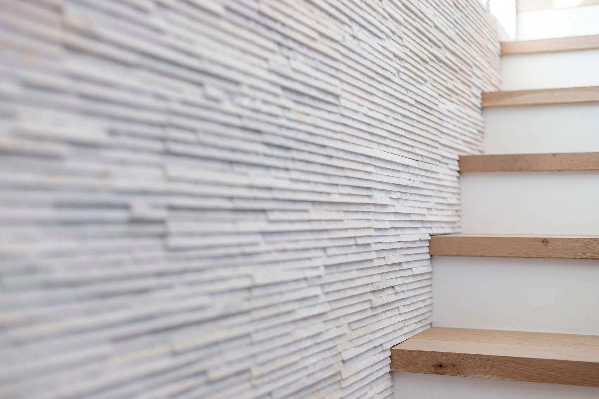 Modern wooden staircase with textured stone wall
