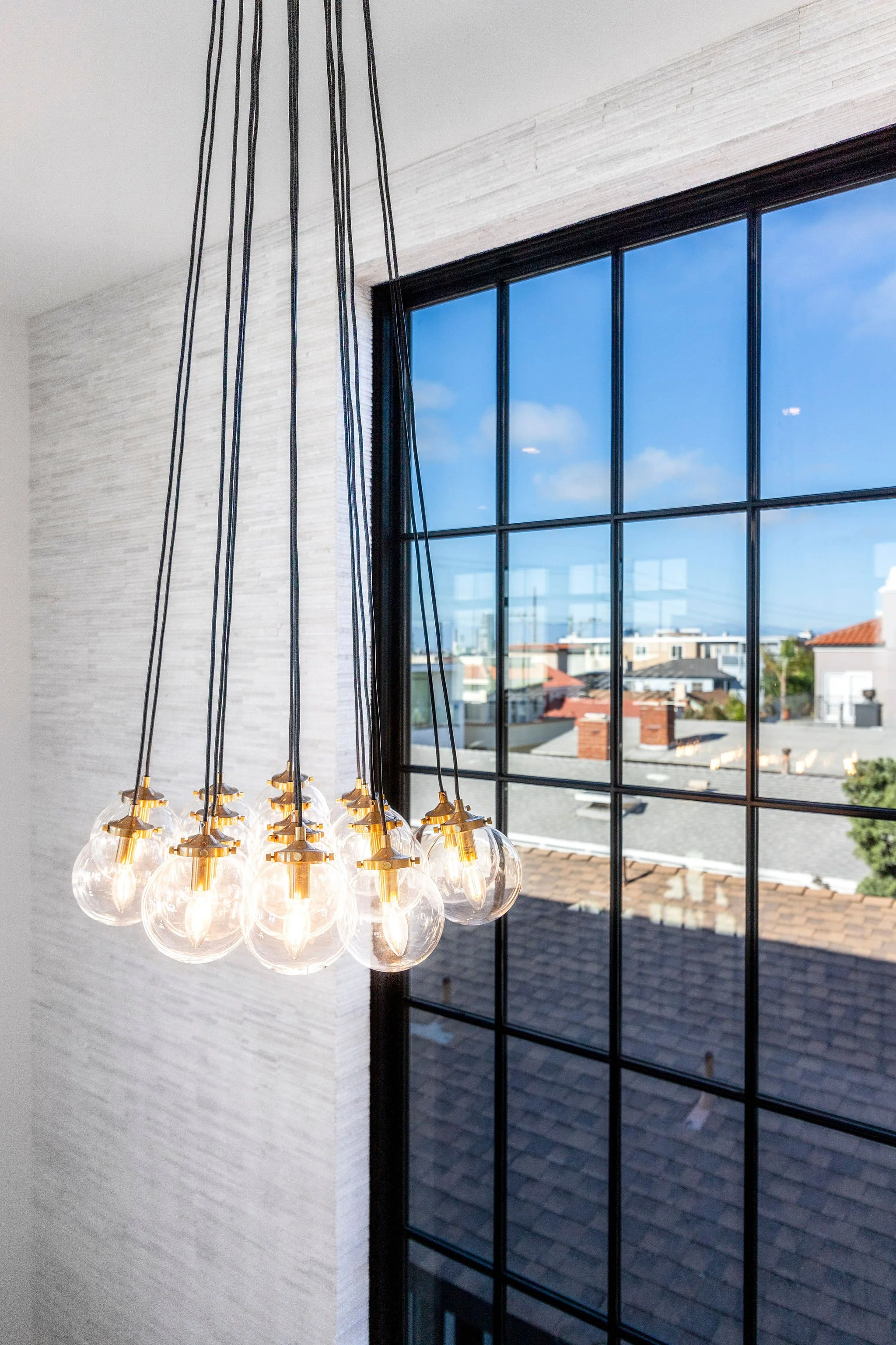 Modern glass pendant lights hanging near large window with cityscape view.