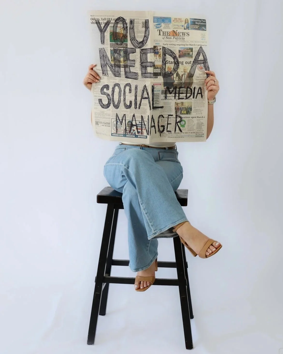 Person sitting on a black stool holding a newspaper with the message 'YOU NEED A SOCIAL MEDIA MANAGER' written over it.