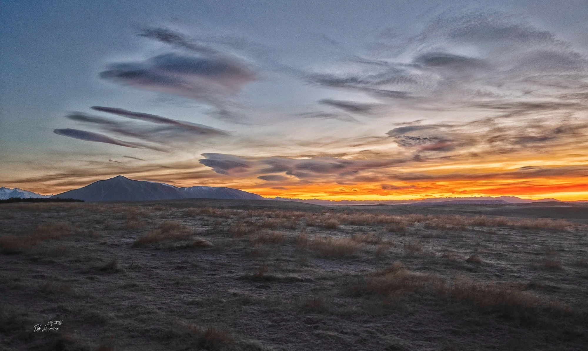 New Zealand has stunning sunset colours graced by ever changing cloud formations, who in turn are sculpted by the wind and weather   High whispy clouds shown here are lenticular cloud indication strong 
The sunset is south of Twizel 
