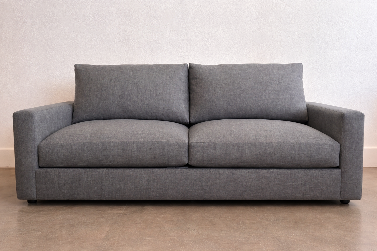 In the background, this charcoal grey two-seat sofa showcases clean lines and tailored comfort. Upholstered in durable performance fabric, it offers a modern, pet-friendly solution for everyday living. A versatile choice for custom sofas and contempo