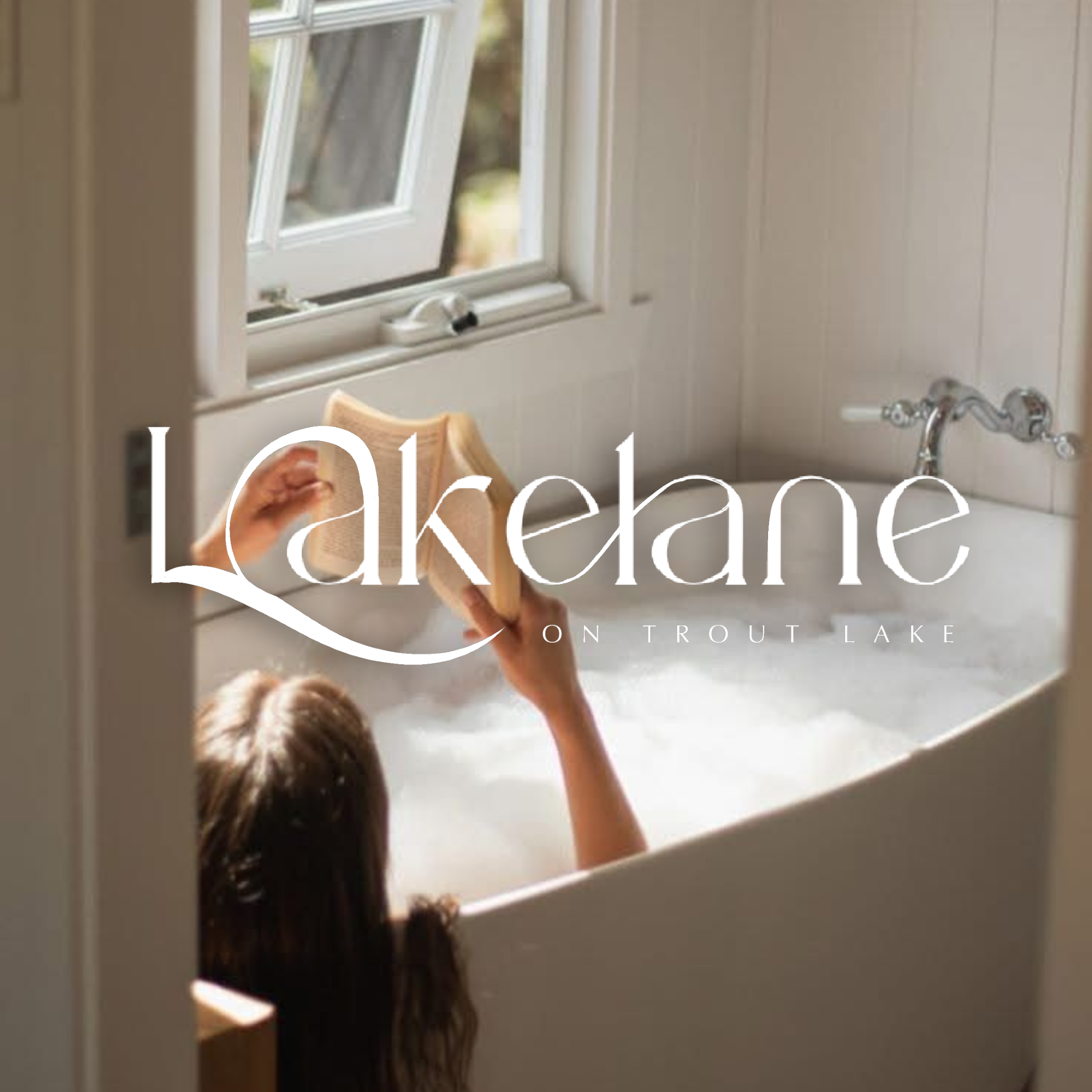 A person reading a book in a bathtub filled with bubbles, near a window. The text on the image says 'Lakedale on Trout Lake'.