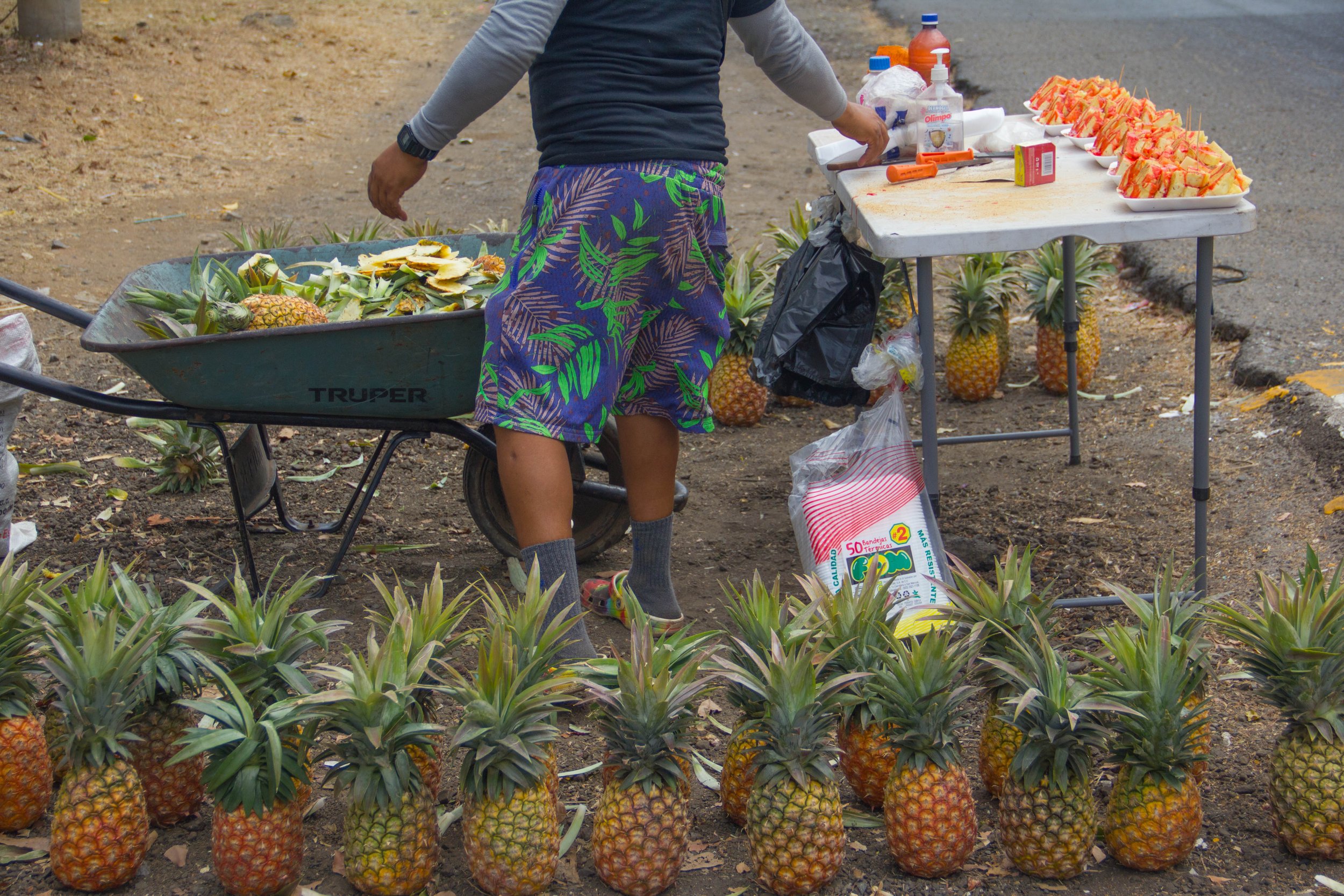 pineapples on the side of the road, being sliced