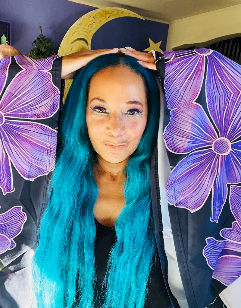 Shaunté Ledger, creative director and brand strategist, with teal hair and purple flowers