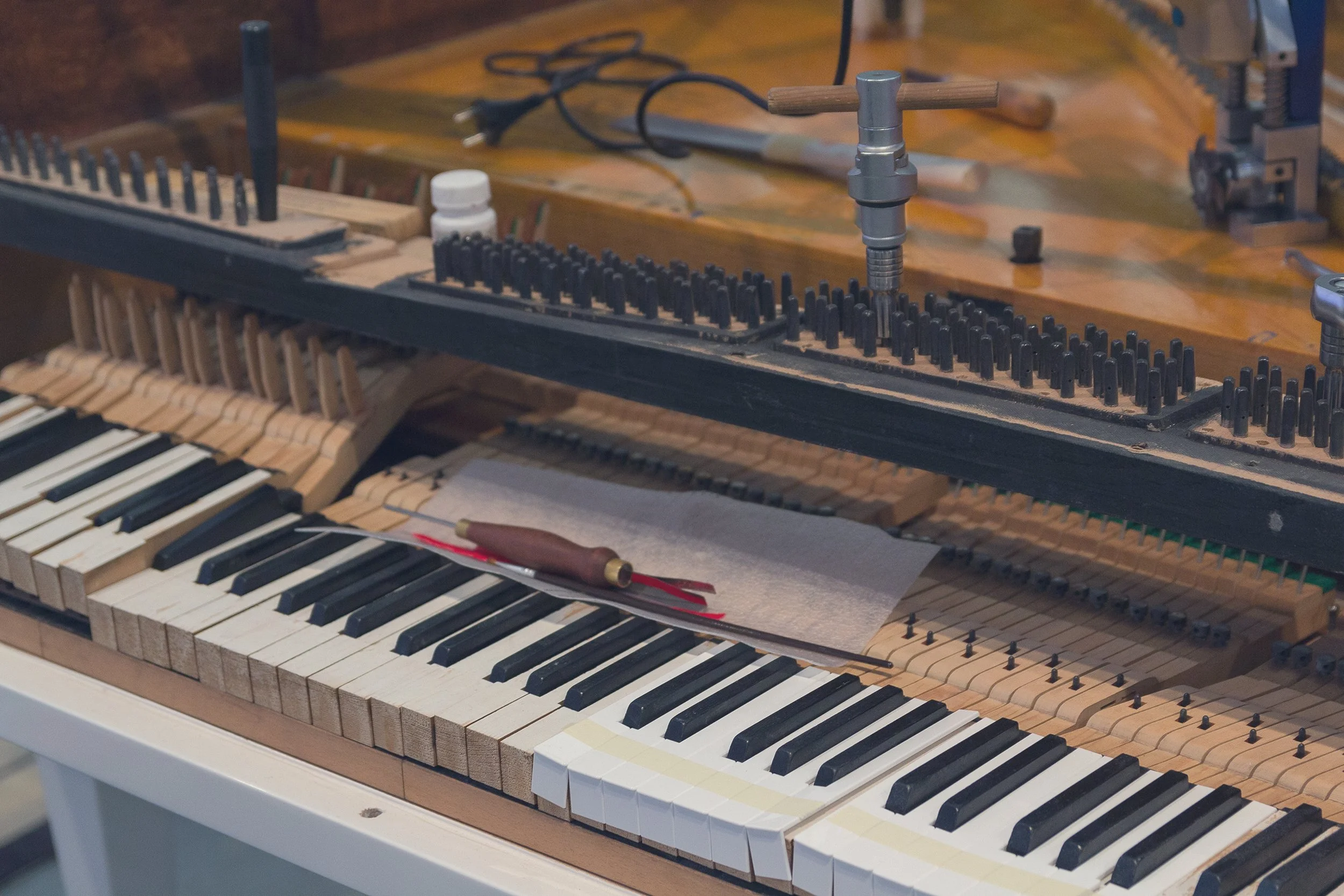 Close-up of a grand piano being repaired by replacing keytops, replacing strings, tuning, and regulation.
