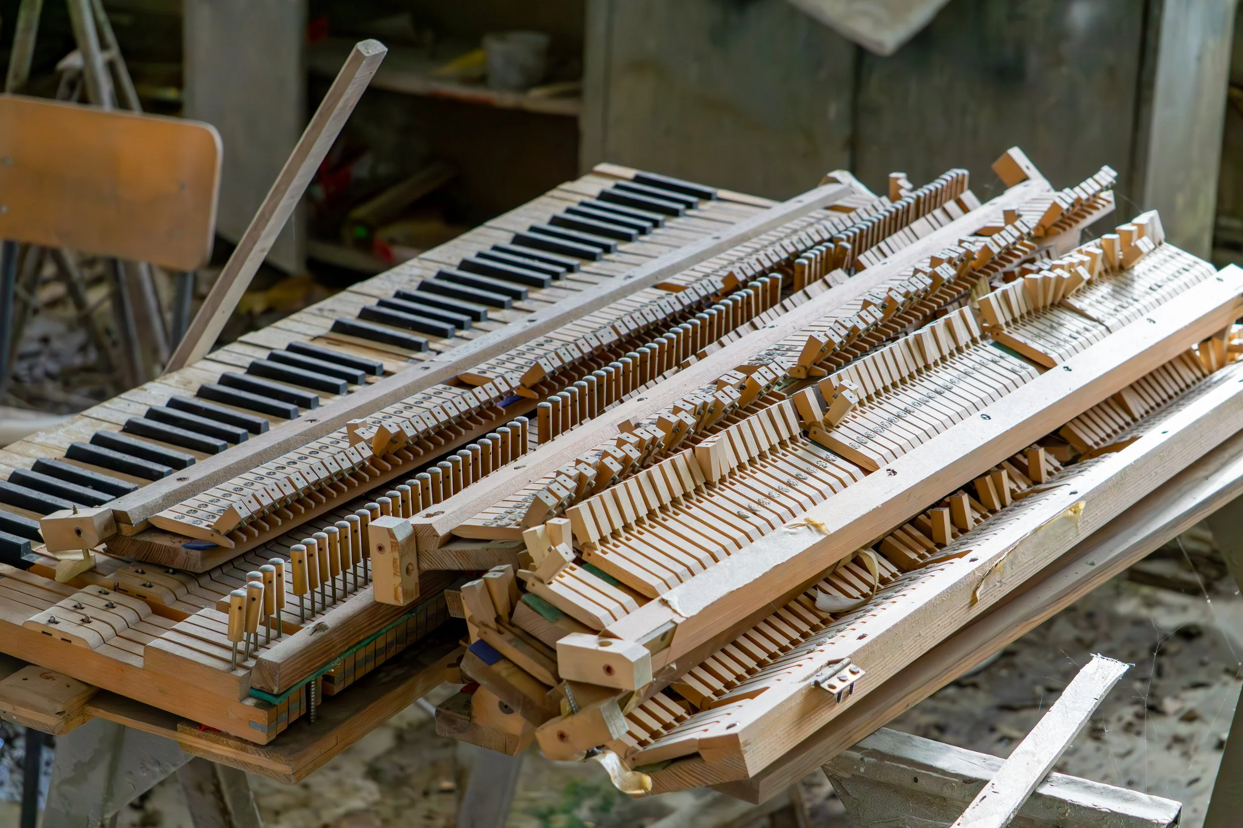 Messy piano action including the piano hammers and keys as well as some damper lift trays.