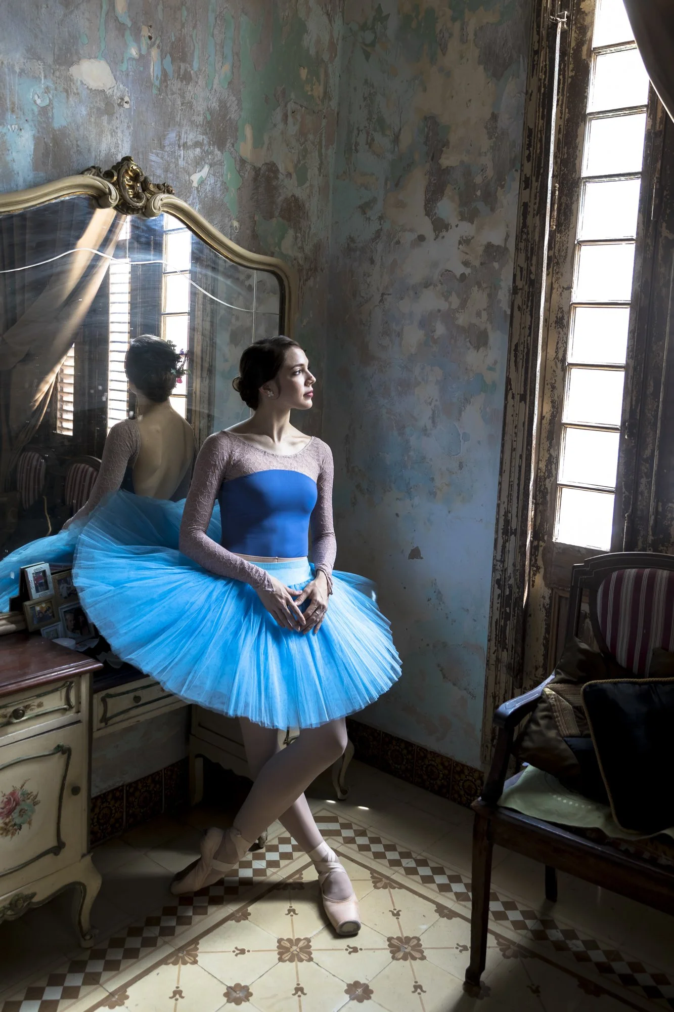 A Cuban ballet dancer stands in the quiet light of an aging Havana mansion. The faded walls behind her mirror the resilience of Cuba’s ballet culture—world-renowned, yet shaped by scarcity and devotion. 