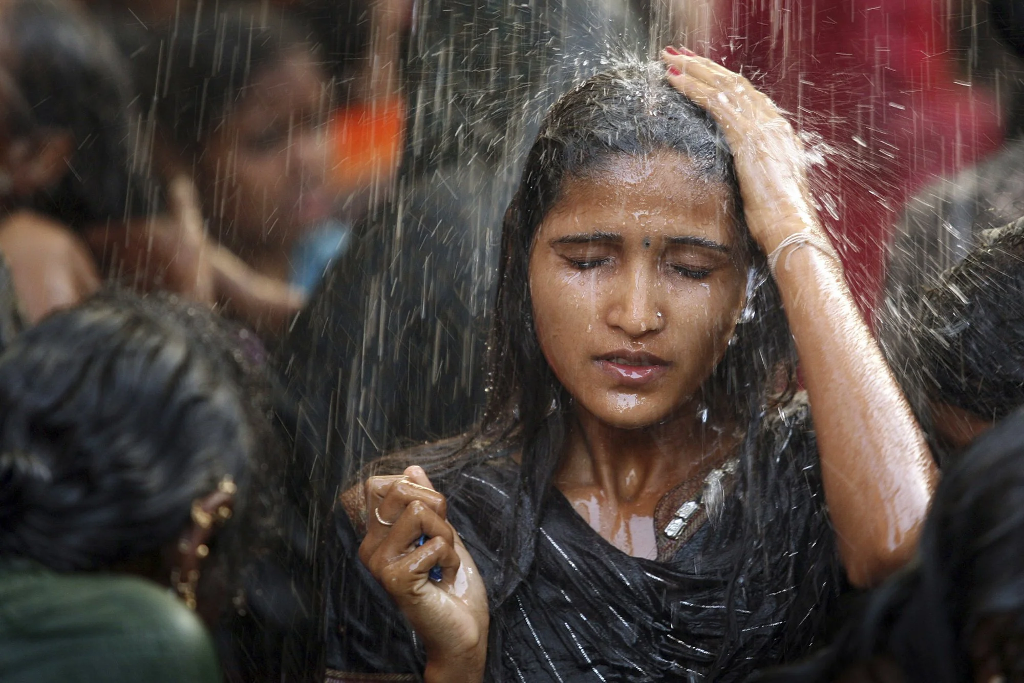 A young woman bathes in a communal shower before entering the Yellamma Temple during the Yellamma Jatre festival in Saundatti, India. The ritual cleansing is both practical and symbolic—a moment of purification before prayer—performed amid the crush 