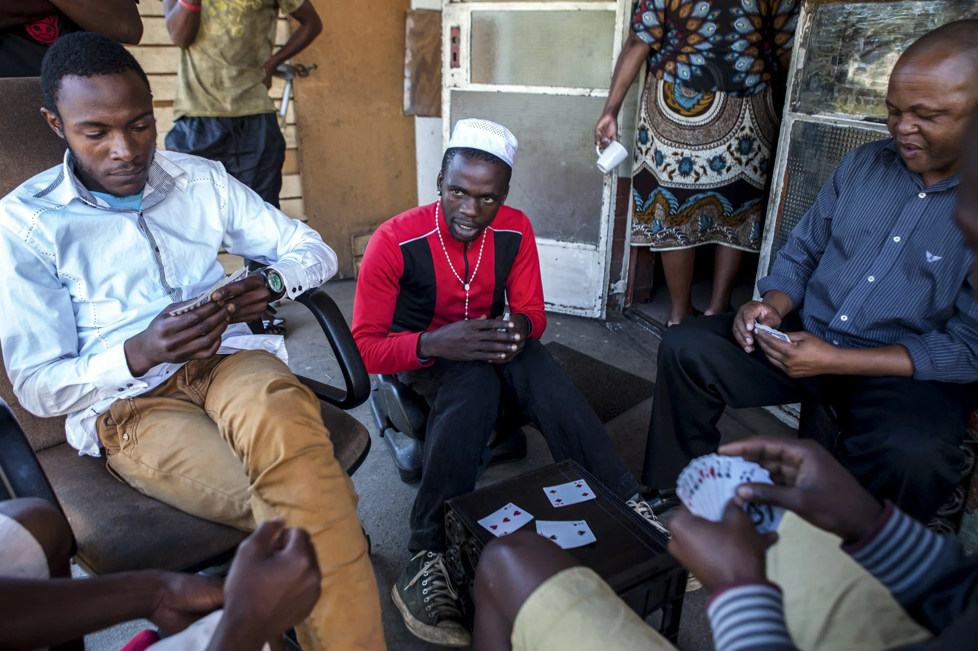 A group of men play casino outside one of the old hostels at “Skomplaas,” a former Durban Deep Gold Mine residence on Johannesburg’s West Rand. Once built to house migrant laborers during the gold boom, these hostels now shelter a new generation of m