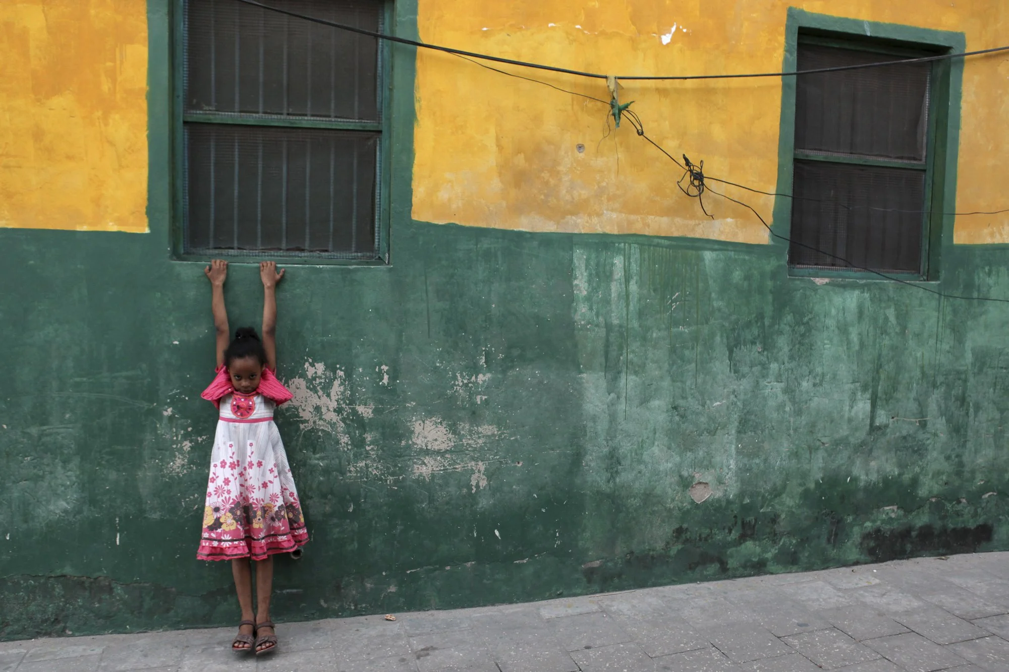 A young girl hangs from a windowsill in Stone Town, Zanzibar—a UNESCO World Heritage site shaped by centuries of cultural exchange along the Swahili coast.