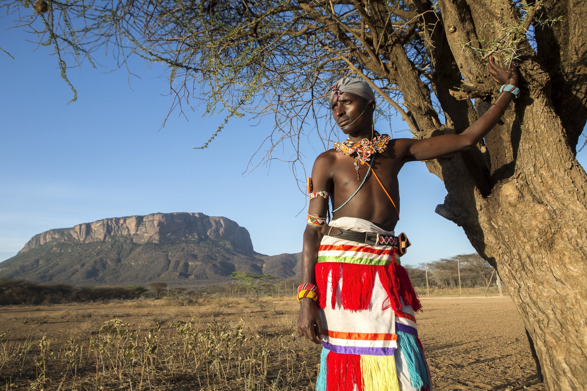 A Samburu warrior, one of my photography students, stands before Mount Ololokwe in northern Kenya. The workshop was created to help Samburu document lion encounters for research—and to provide a tool for safely recording their own interactions with a