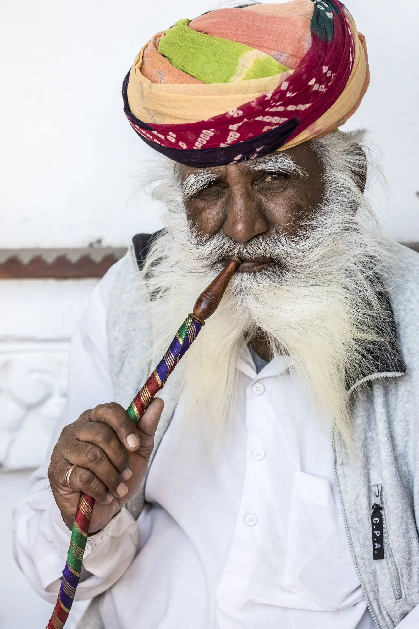 A Rajasthani man smokes his hookah, his vibrant turban and sweeping mustache echoing the cultural pride and traditional identity of the region.